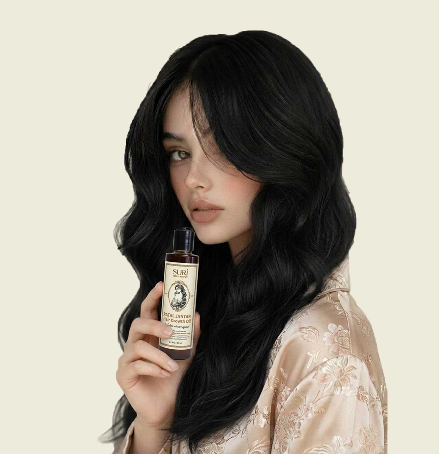 Woman with long, wavy black hair holding Suri Herbal Lounge Patal Jantar Hair Growth Oil bottle.